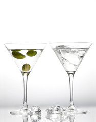 Martini glasses with green olives and pieces of melting ice