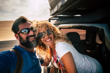 Cheerful adult happy caucasian couple enjoy travel with car and take selfie picture smiling...