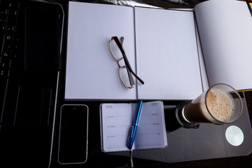 Books, notebook, pen, mobile phone, glasses and coffee latte.