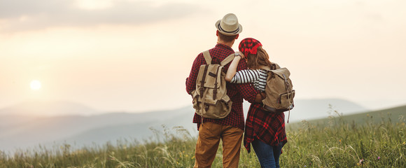 happy couple man and woman tourist at top of mountain at sunset   a hike in summer.