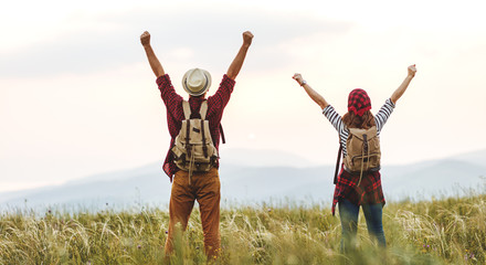 happy couple man and woman tourist at top of mountain at sunset   a hike in summer.