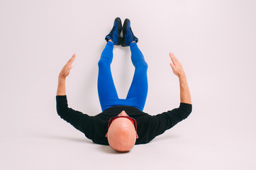 Fashion portrait of stylish man in blue tights and indigo boots stretching and exercising over...