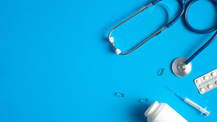 Medical equipment, tools, supplies on blue background. Flat lay stethoscope, syringes, pills. Medical banner design. Healthcare and medicine concept.