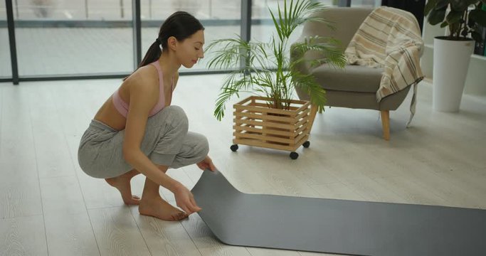 Young Beautiful Woman Practicing Yoga, Gray Fitness Mat Roll Out Slow Motion