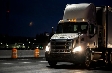 Big rig white day cab semi truck transporting cargo in semi truck driving on the wet rainy road in dark night time © vit