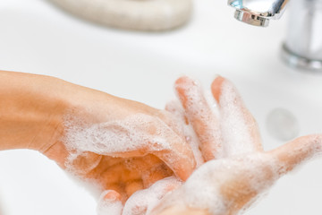 Fototapeta premium a Washing hands with soap under the faucet with water