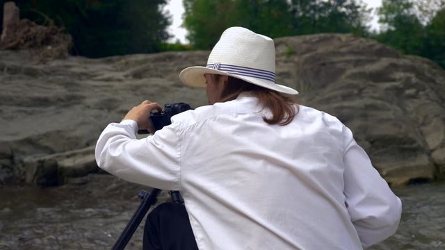 Videographer Shoots Footage On Rocks Near Mountain River. Filmmaker Camera Operator. Slow motion 4k 30p 0.5 speed of 60p