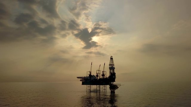 Aerial view of the jack up rig shot during sunset time. Fly around the jack up rig with a drone.