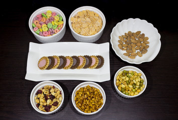 Variety of healthy food like peanuts, cereal, cookies and almonds. 