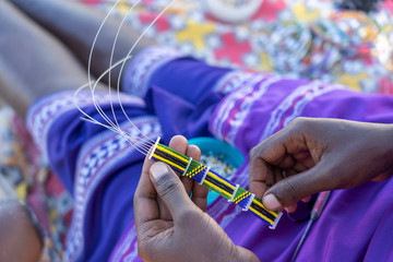 Making of handmade jewellery. Masai african women hands, top view, close up. Island of Zanzibar,...