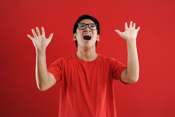 Naklejka premium Young asian man happy and excited expressing winning gesture. Successful and celebrating