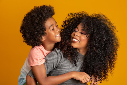 Portrait of young African American mother with toddler son. Yellow background. Brazilian family.