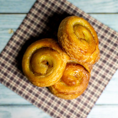 Homemade glazed puff pastry rolls on a dark blue wooden background. Shallow depth of field. Selective focusing