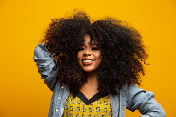 Beauty portrait of african american woman with afro hairstyle and glamour makeup. Brazilian woman. Mixed race. Curly hair. Hair style. Yellow background.