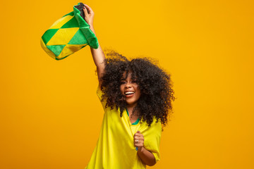 Brazil supporter. Brazilian woman fan celebrating on soccer or football match on yellow background....