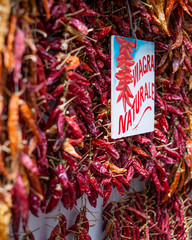 Local dried red peppers at a food market for sale. Clumped together for a nice display. Sign translates from Italian to English as "Natural Viagra".