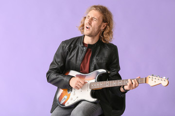 Obraz premium Man playing guitar and singing on color background