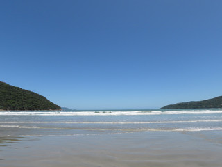Sea, sand, mountains, sun and blue sky. Beach in the city of Ubatuba. Interior of São Paulo. Brazil.