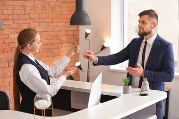 Female receptionist handing room key to man in hotel