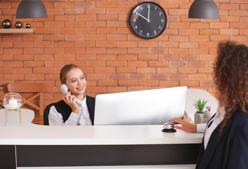 Young female receptionist working with guest in hotel