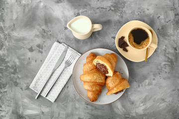 Plate with tasty sweet croissants and coffee on grunge background