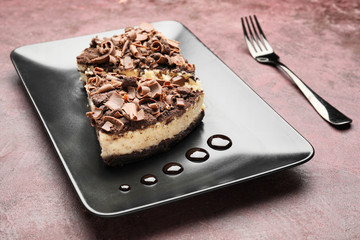 Plate with tasty chocolate cheesecake on color background