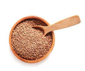 Bowl with raw buckwheat on white background