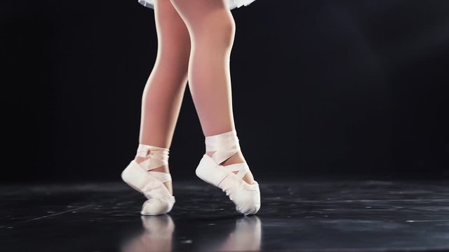 Beautiful baby feet in ballet flats ballerinas cross the stage. Close-up. Slow motion