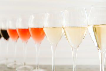 Wine tasting set in the light airy environment. Custom wine tasting concept. Glasses of wine and bottles on the glass table and light background.