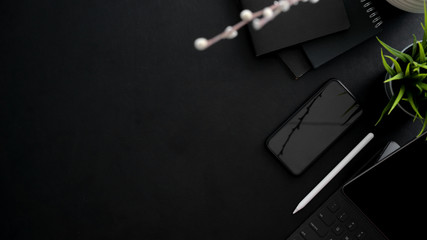 Top view of dark modern workplace with smartphone, tablet, office supplies and copy space