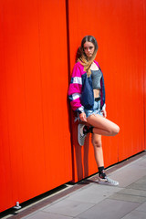 Fototapeta na wymiar Teenager girl standing and leaning against bright orange doors.