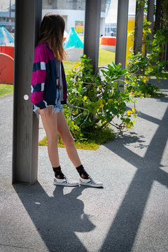 Teenage girl below standing leaning against post