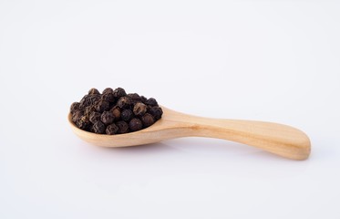 Top view of black pepper in wooden spoon isolated on white background.