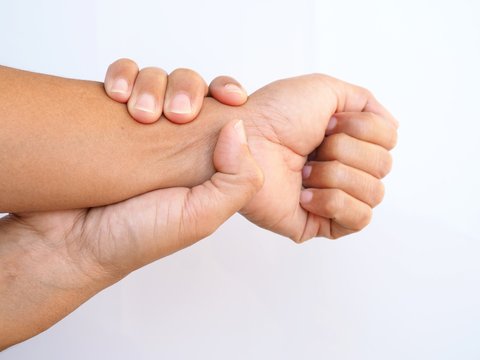 Asian adult suffering from wrist pain, use hand touch on arm and massage on wrist to relieve, body part isolated on white background.