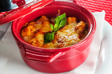 Lasagna on the table with green leaf above.
