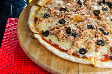 Hot pizza slice with melting cheese on table.