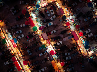 Aerial view at night market. There are many people, cars and shops.