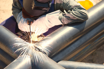 Workers are using welding machines to work on steel pipes for use in construction. Welding of structural pipes requires work skills. technician engineer build iron flame connect structure in workplace