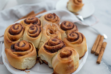 Obraz na płótnie Canvas Cinnamon rolls with sugar frosting. With cinnamon sticks and spices, wooden background