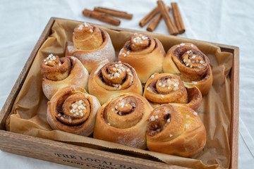 Cinnamon rolls with sugar frosting. With cinnamon sticks and spices, wooden background