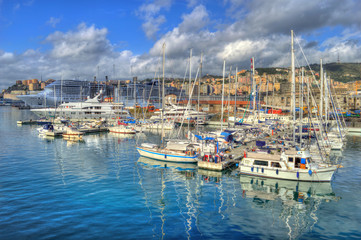 Fototapeta na wymiar Genoa, Italy - Nov 3th 2013: Boats in Genoa harbor, with HDR effect applied. Clouds and hills in the background.