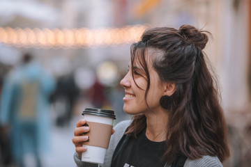 young pretty woman at city street drinking coffee from disposable cup