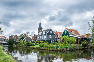 Fototapeta na wymiar View of canal, bridge and traditional wooden fishing houses in waterland village Marken, Netherlands. Traditional Holland symbols - canal, wooden houses, bridge