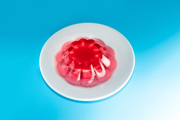 pink fruit jelly in a white plate on a blue background