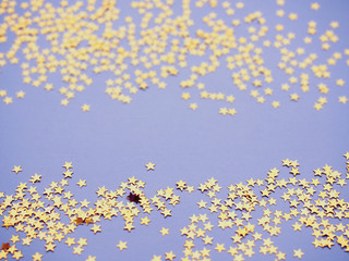 Golden stars glitter on lavender paper background