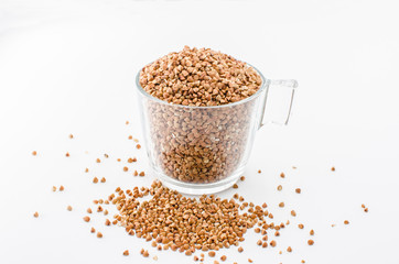 Buckwheat in a glass cup isolated on white background, healthy diet consisting of gluten free grain. Glass cup with raw buckwheat