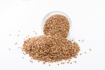 Buckwheat in a glass cup isolated on white background, healthy diet consisting of gluten free grain. Glass cup with raw buckwheat