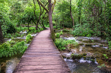 Wooden path over mountain river in Krka Natinal Park, Croatia. Road in the forest over shallow river.
