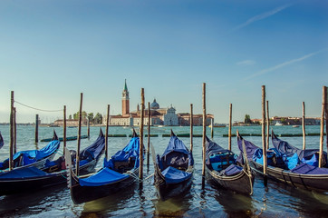 Fototapeta na wymiar Gondolas pier row anchored on Canal Grande with San Giorgio Maggiore church in the background, Venice, Italy