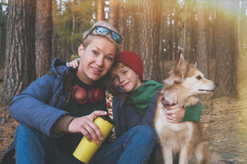 Charming little boy with a beautiful mother in headphones and a red dog on the autumn lawn